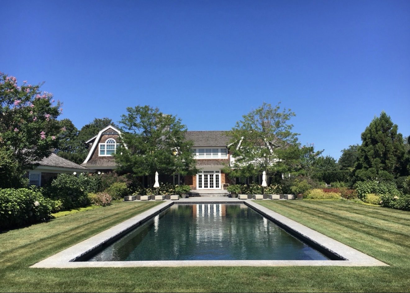 Shingle-style estate home with manicured lawns and a long reflecting pool